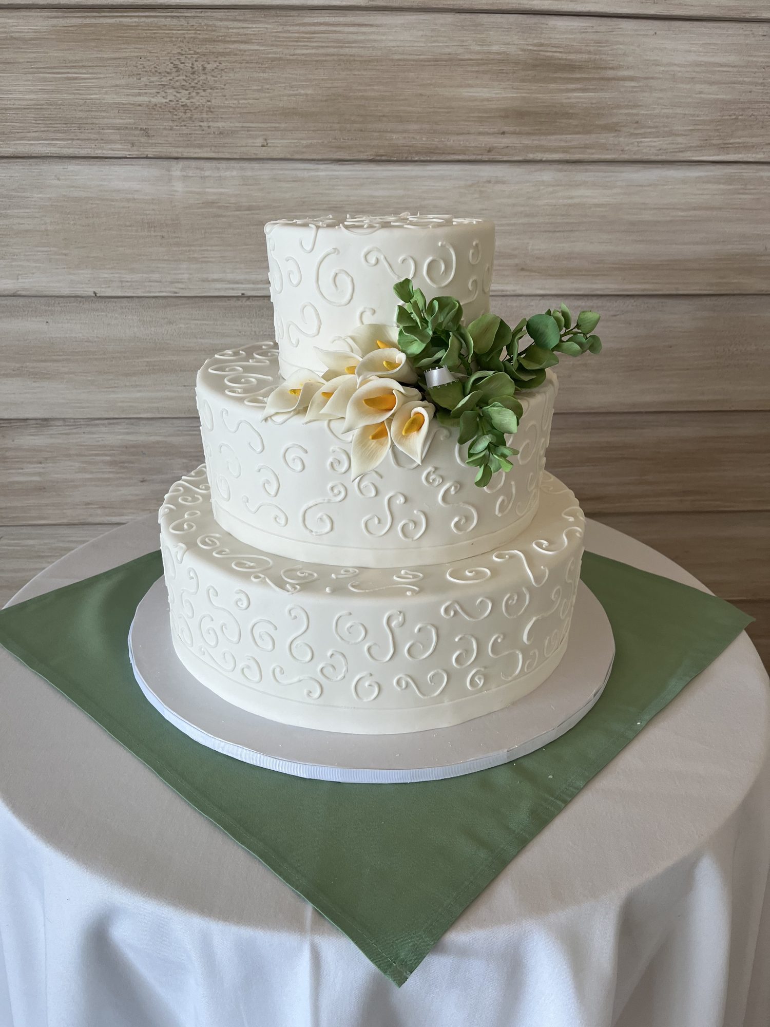 Two-tier wedding cake with eucalyptus and calla lilies